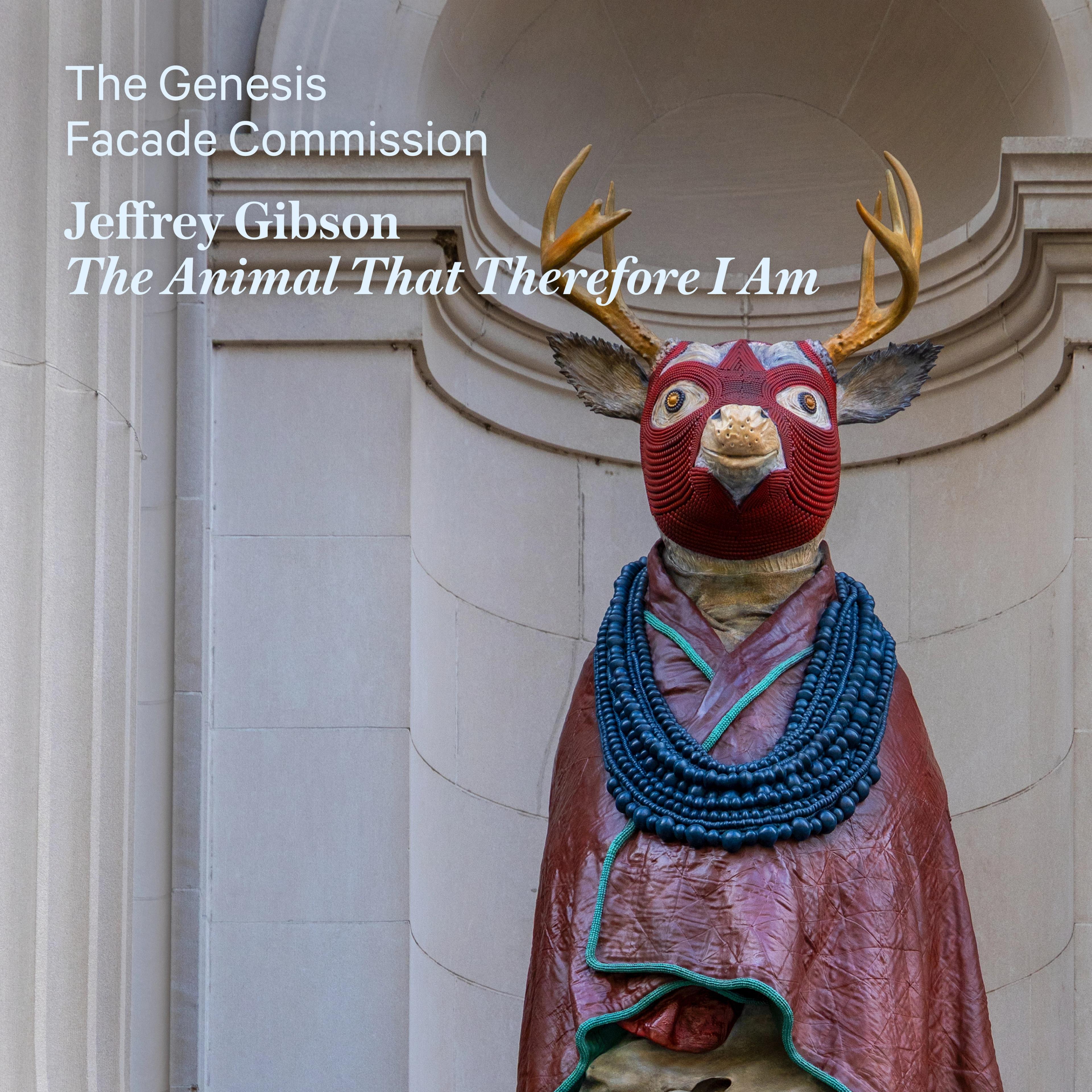 A statue of a deer with a red tribal mask and antlers stands in front of an ornate stone facade. Text reads “The Genesis Facade Commission, Jeffrey Gibson, The Animal That Therefore I Am.”