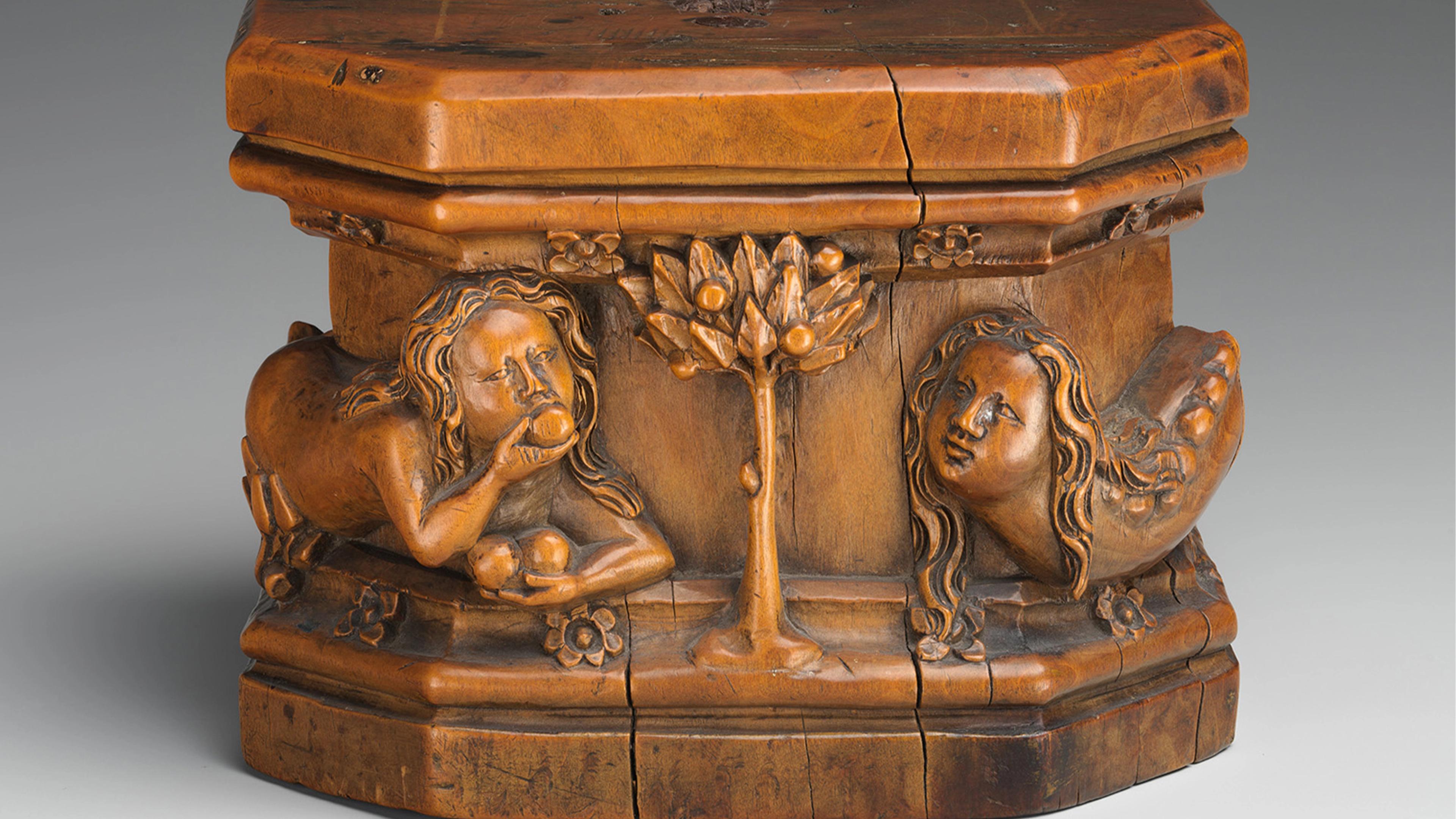 A small wooden carved box featuring figures and a tree in relief.