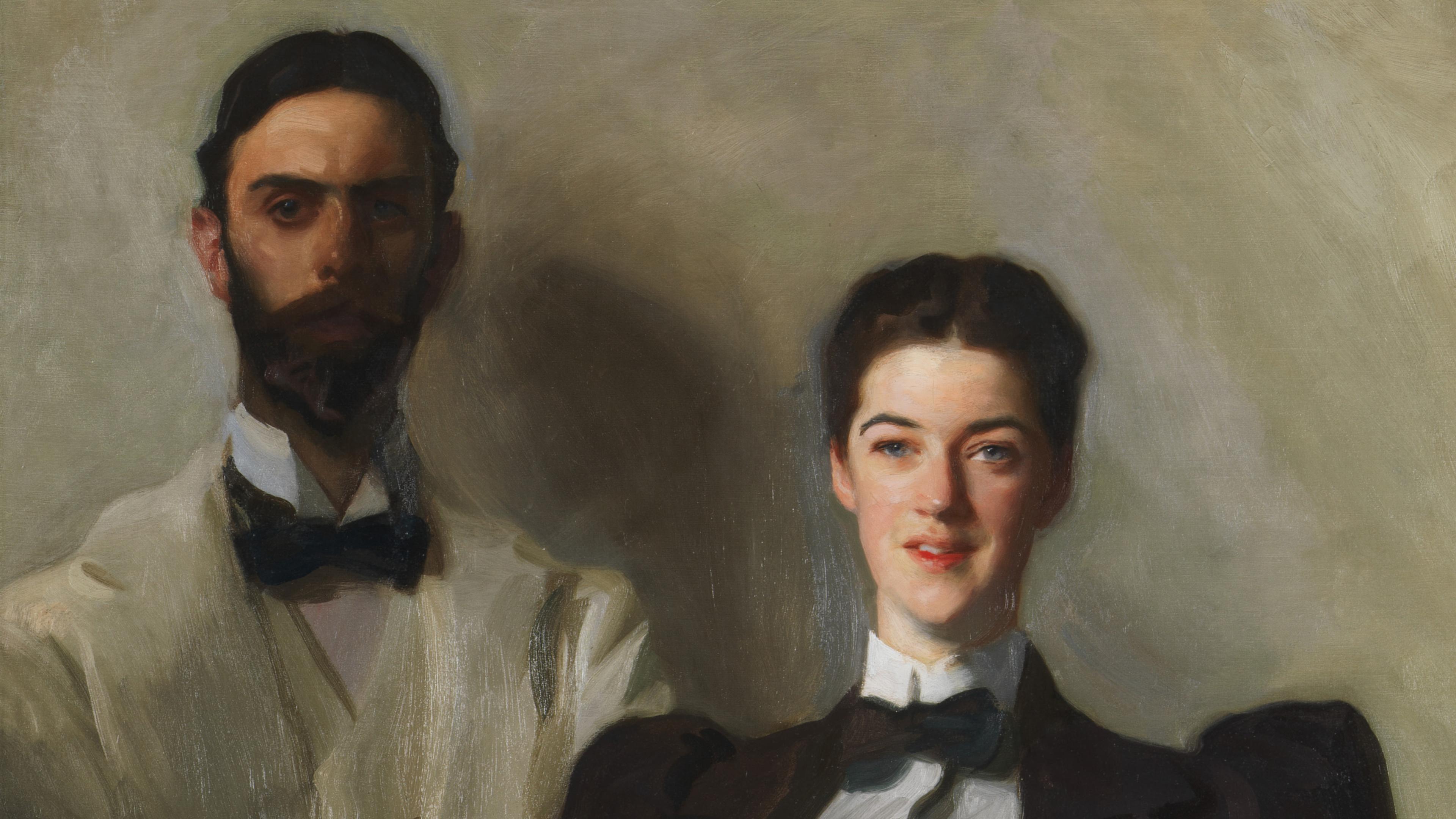 Portrait of a couple, both sharply dressed in jackets with bowties. The man stands in the background, his face partially obscured in shadows, while the woman's face is brightly lit and curious.