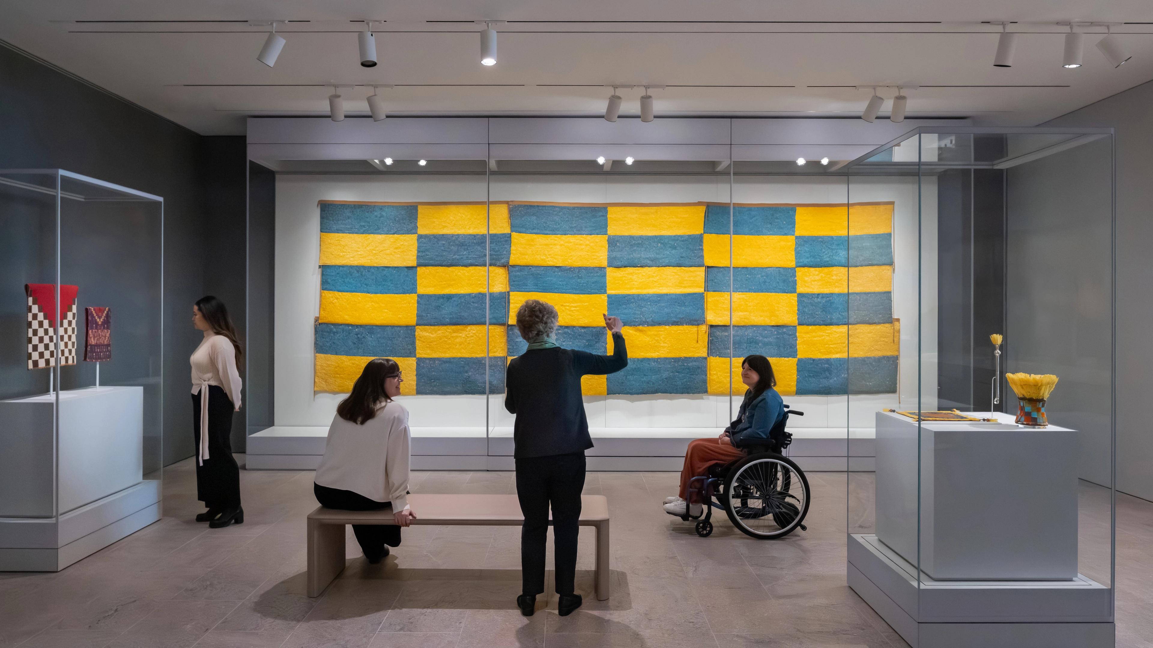 Woman talking to a group in front of the Nine Feathered Panels in Gallery 363, Arts of the Ancient Americas, The Michael C. Rockefeller Wing.