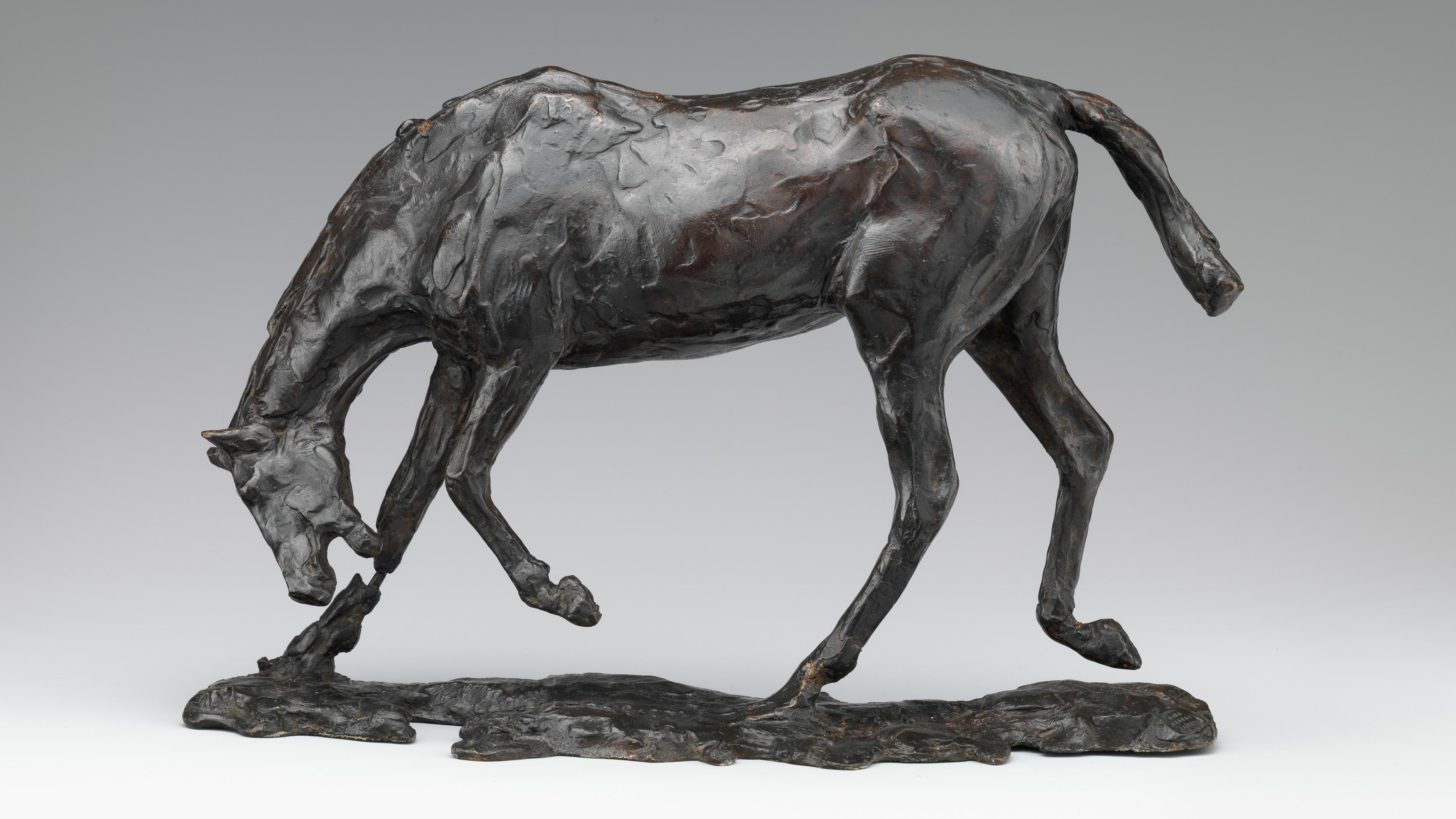 Brown-black sculpture of a horse in motion, its head angled towards the ground and mouth open.
