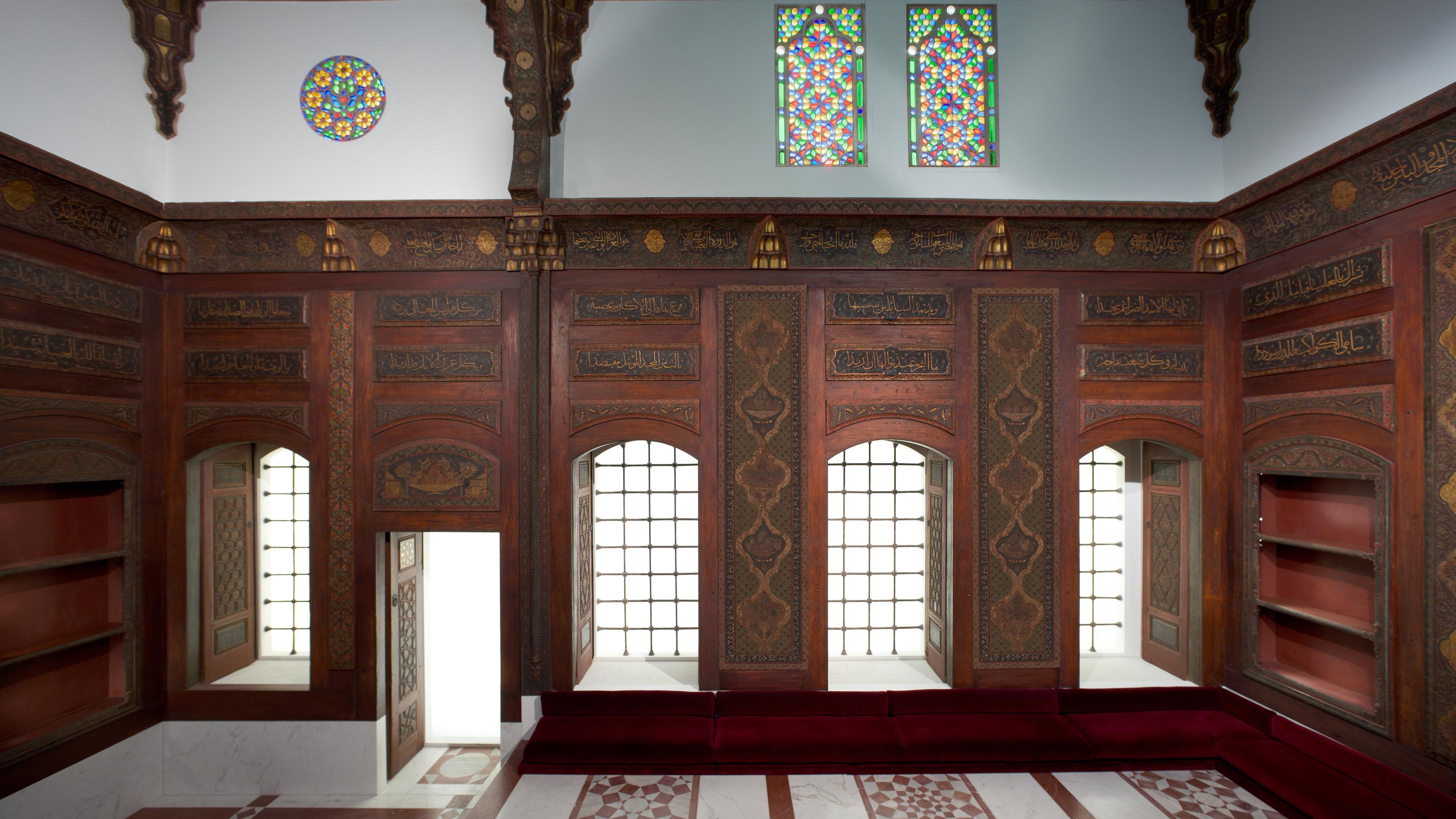 Ornate room with elegantly paneled walls, stained glass windows, and a geometric tiled floor.