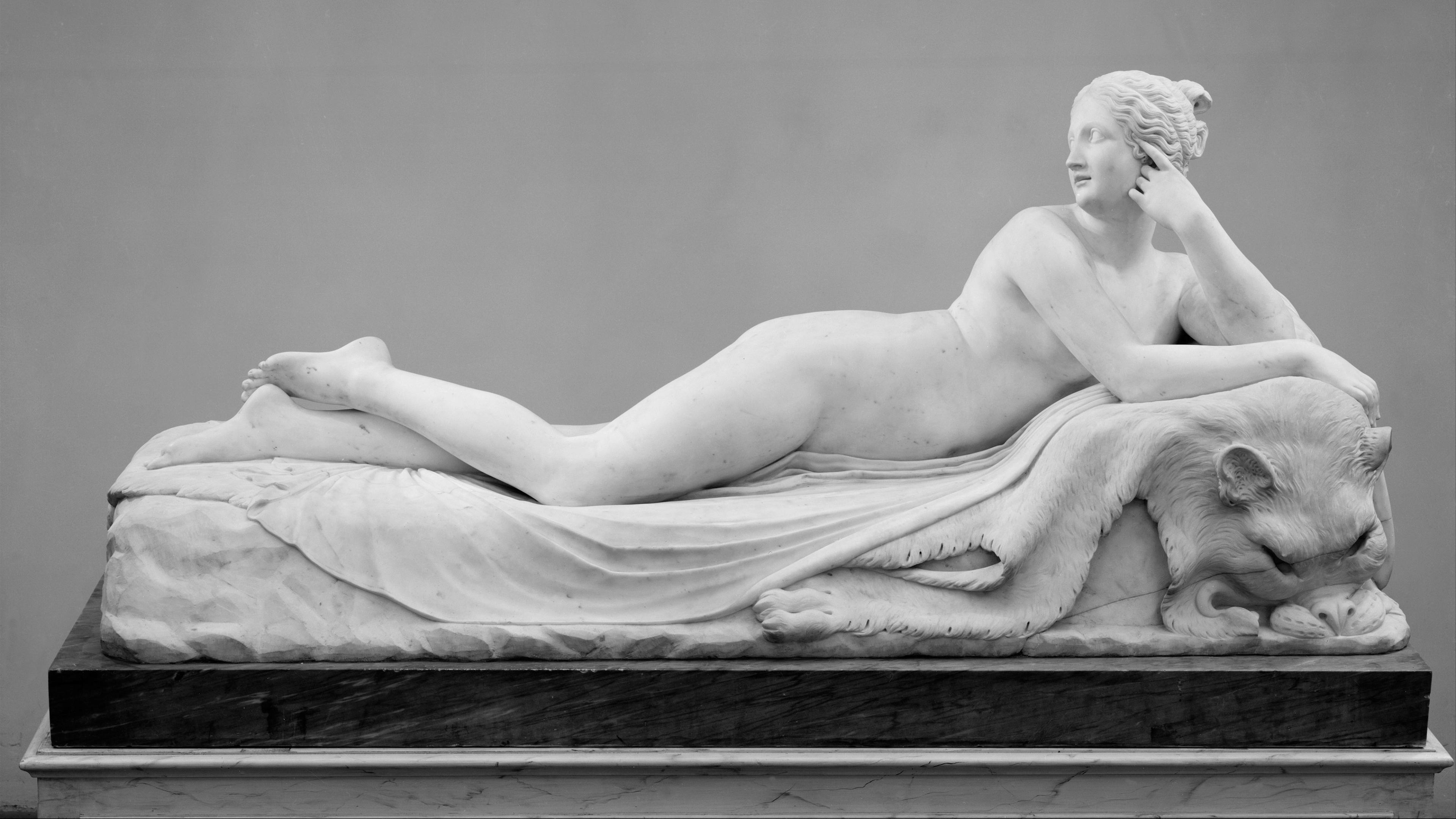 Sculpture of a nude woman reclining on a bed.